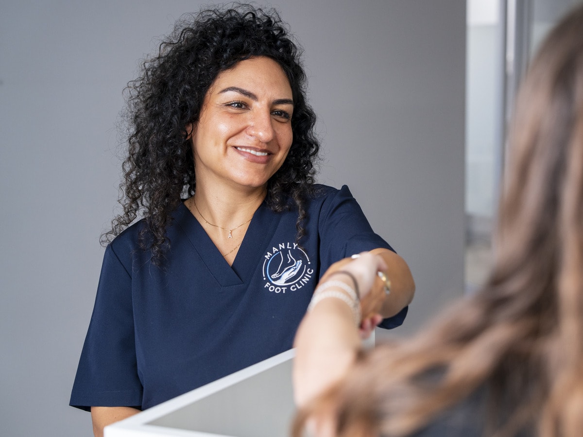 A podiatrist helping a patient at the front desk of Manly Foot Clinic
